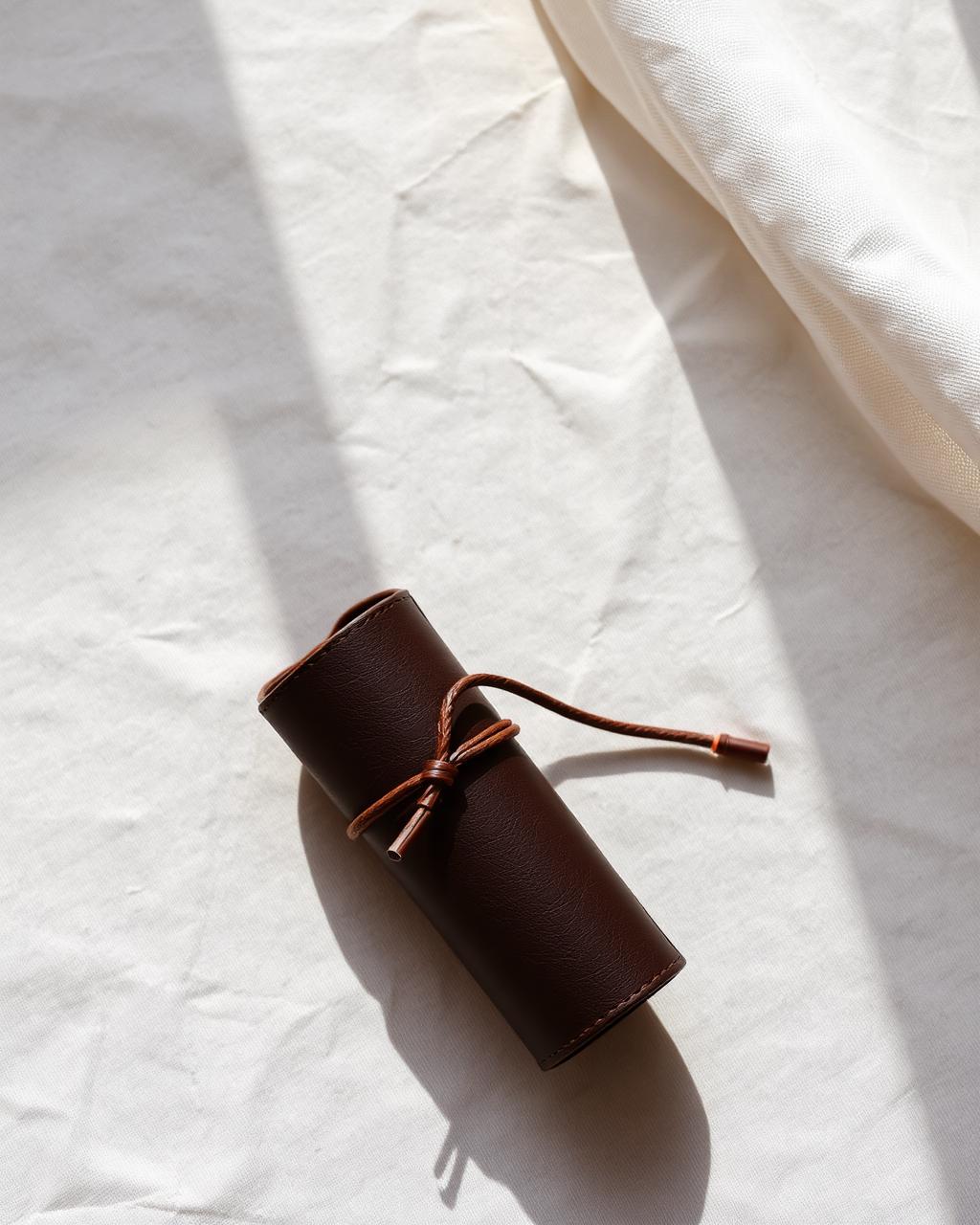 Rolled leather cable pouch tied with a cord