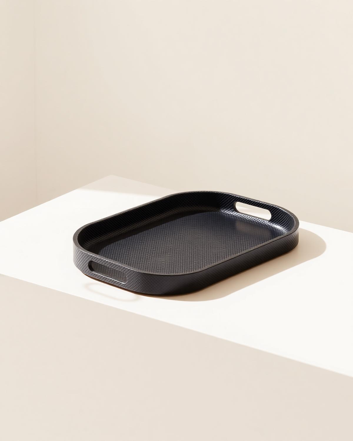 Carbon fibre tray resting on a pale plinth