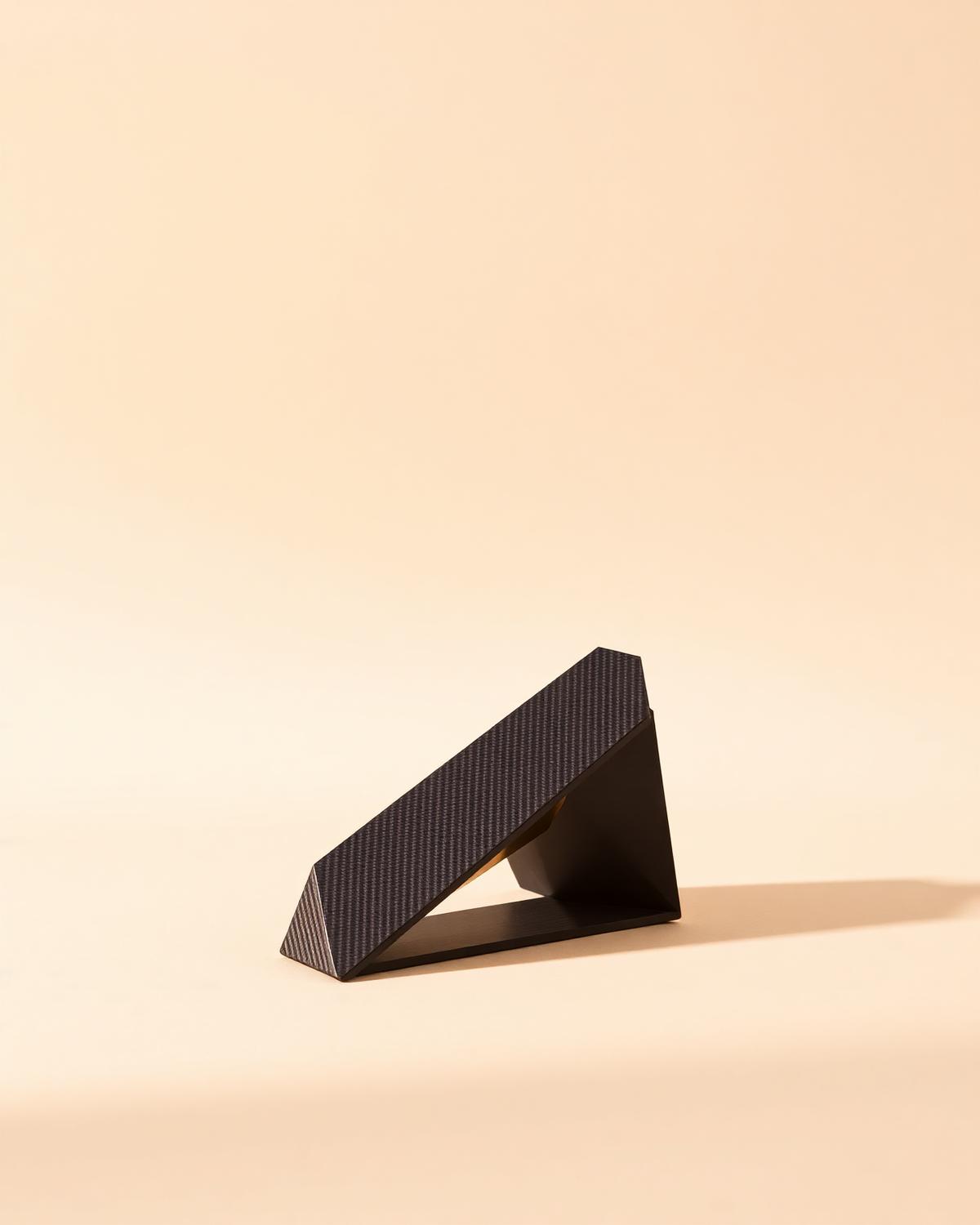 Angular carbon fibre object on a warm backdrop