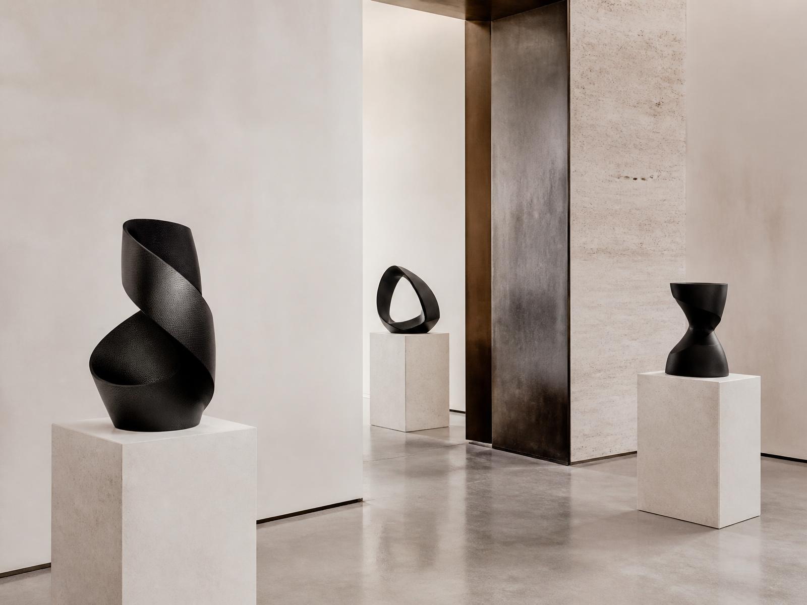 Minimal plaster gallery with carbon fibre sculptures on travertine plinths