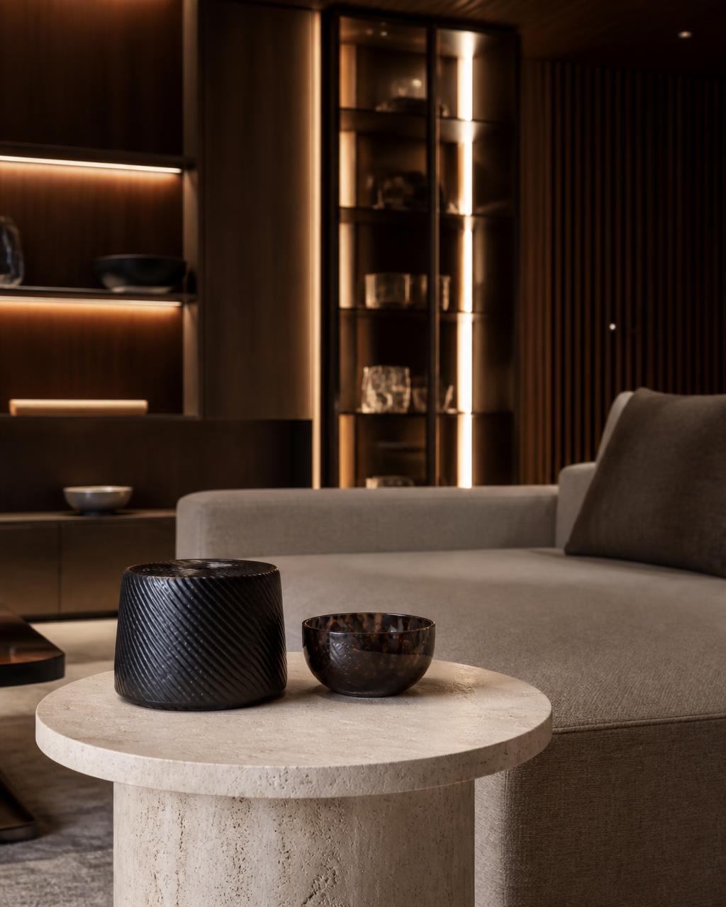 Warm evening lounge with a carbon fibre vessel and bowl on a travertine side table