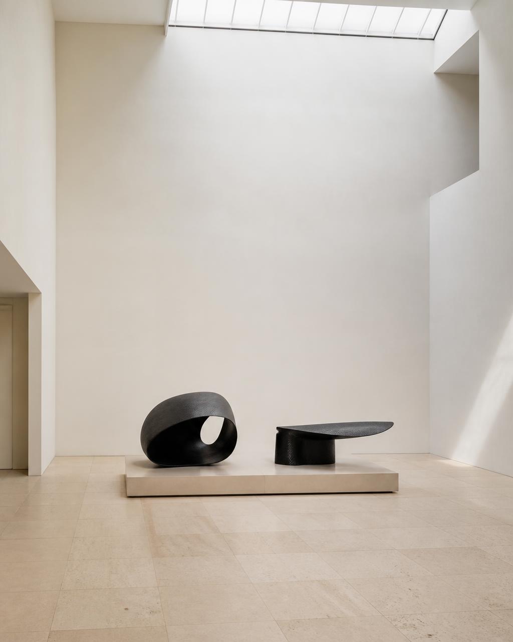 Skylit gallery room with two carbon fibre sculptures on a low limestone plinth